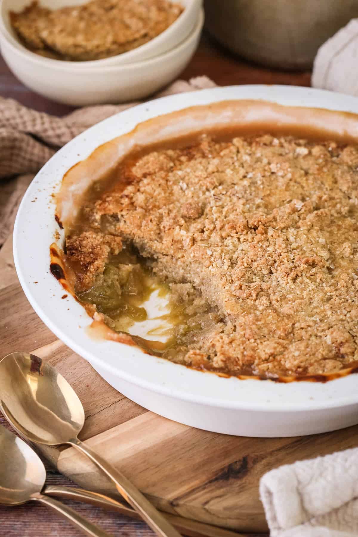 Gluten-Free Rhubarb Crumble in baking dish. with a portion removed showing thick and jammy rhubarb filling.