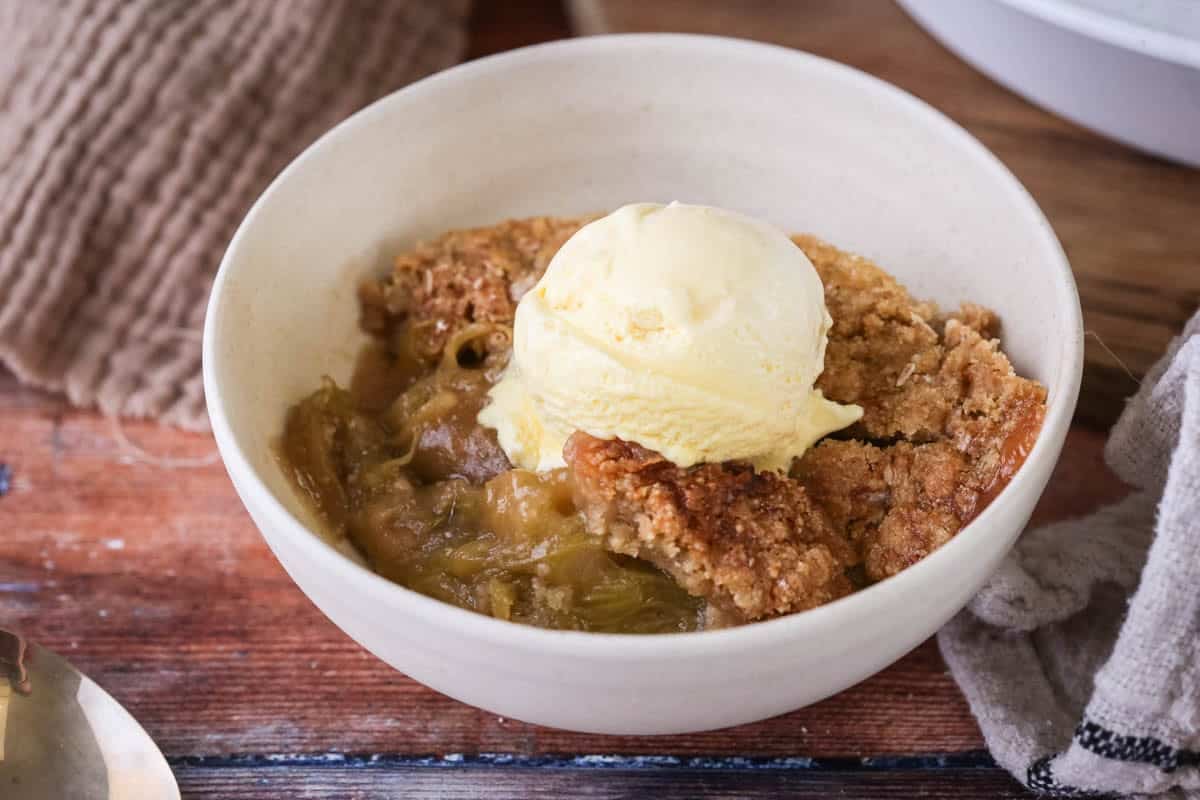 Gluten-Free Rhubarb Crumble served into a bowl with ice cream melting on top.