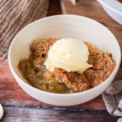 Gluten-Free Rhubarb Crumble served into a bowl with ice cream melting on top.