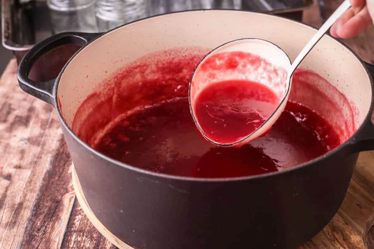 Ladle spooning out raspberry jam.