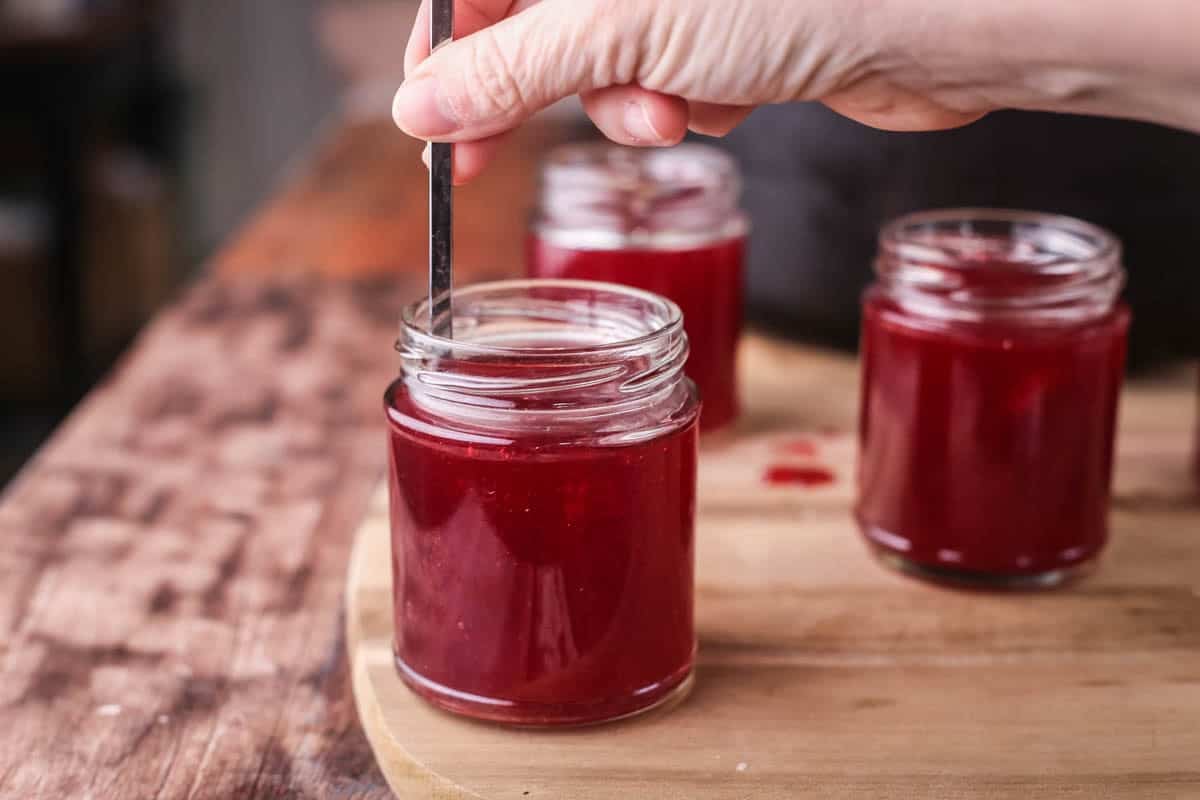 skewer removing air bubbles from raspberry jam after potting and prior to sealing.