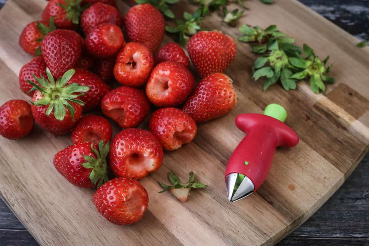 Strawberry huller removing stems and hulls from strawberries.