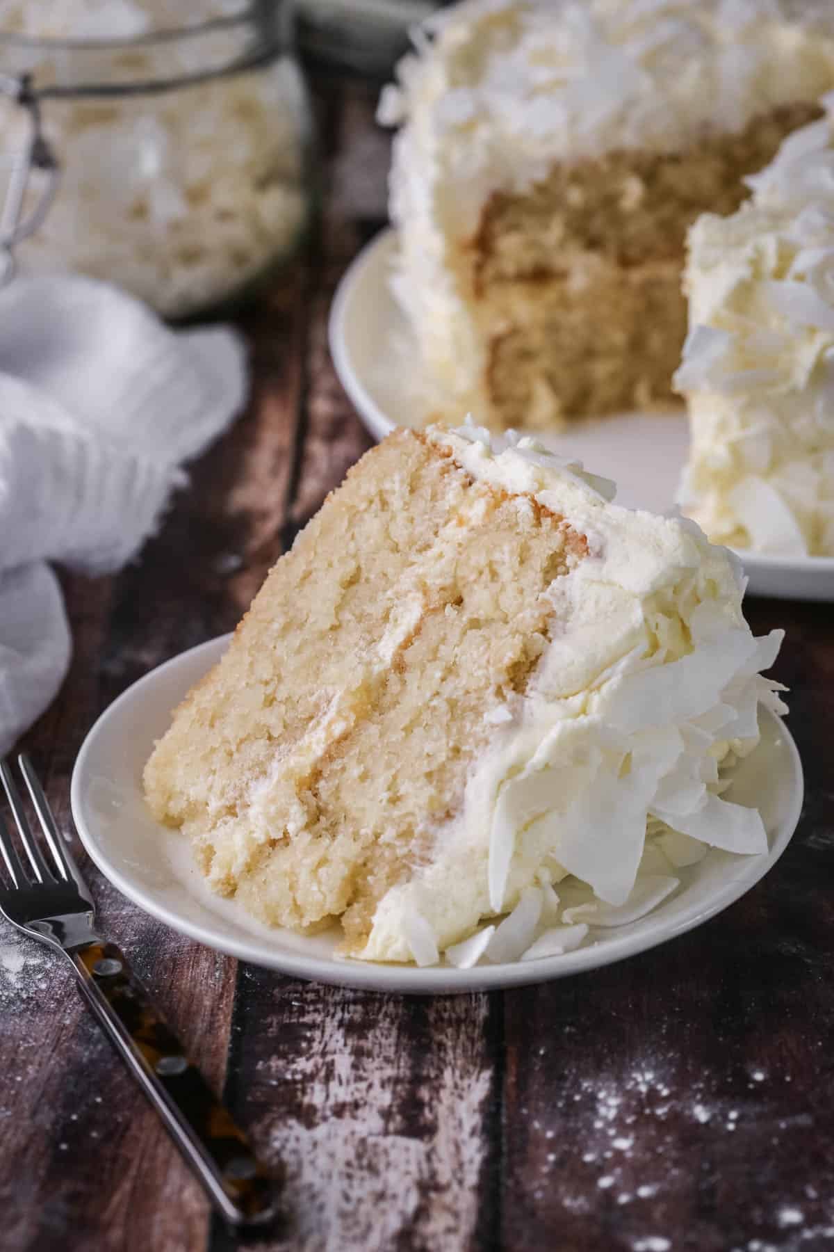 Soft, moist and fluffy slice of gluten-free Coconut Cake on a plate showing the tender crumb.