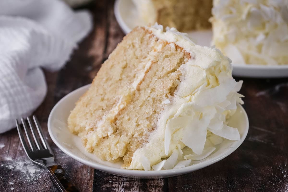 Soft, moist and fluffy slice of gluten-free Coconut Cake on a plate showing the tender crumb.