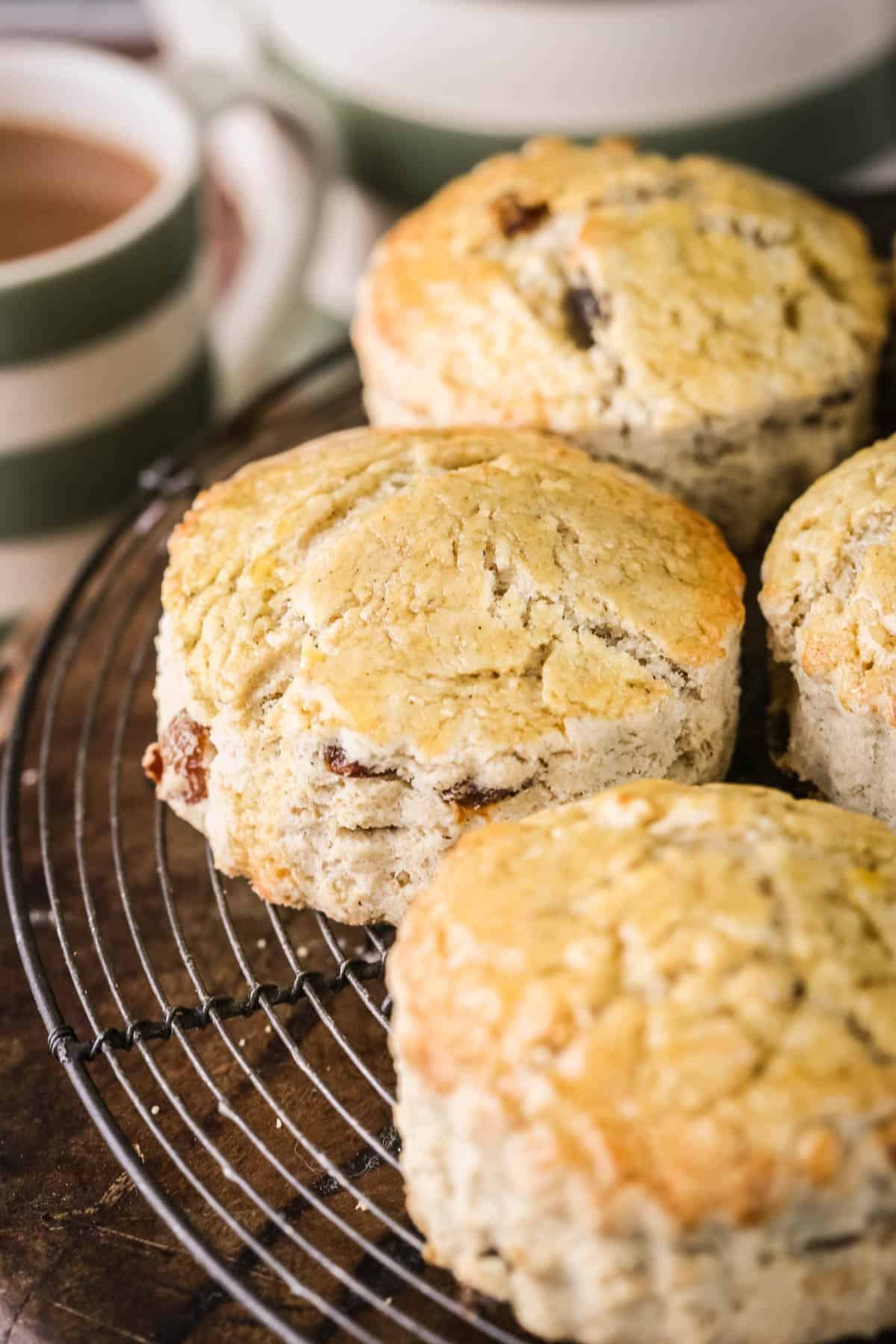 Gluten-free fruit scones on a wire rack next to a cup of tea.