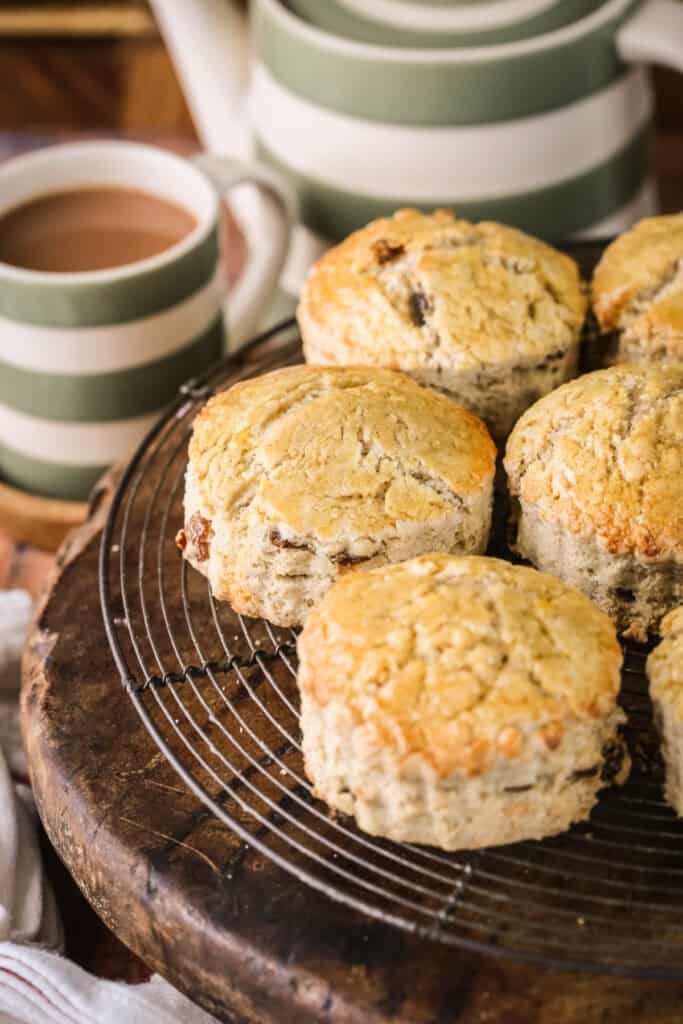 Gluten-free fruit scones on a wire rack next to a cup of tea.