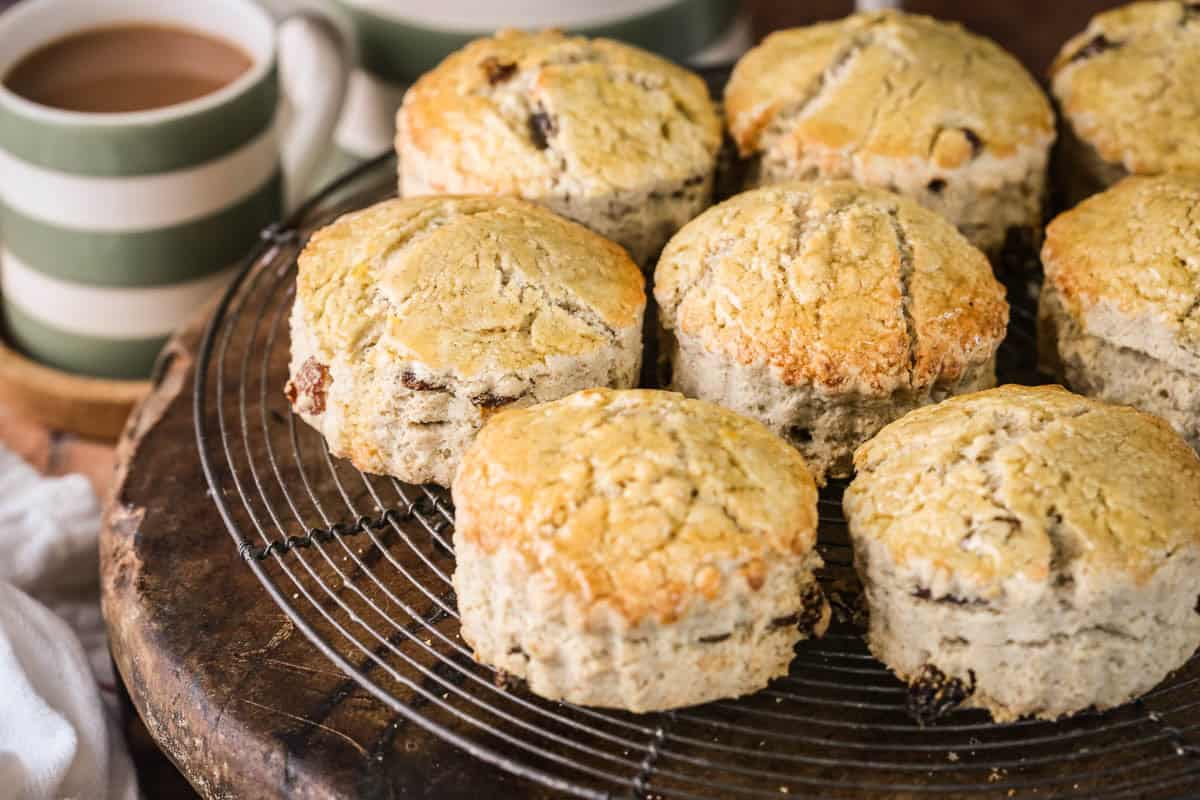 Gluten-free fruit scones on a wire rack next to a cup of tea.