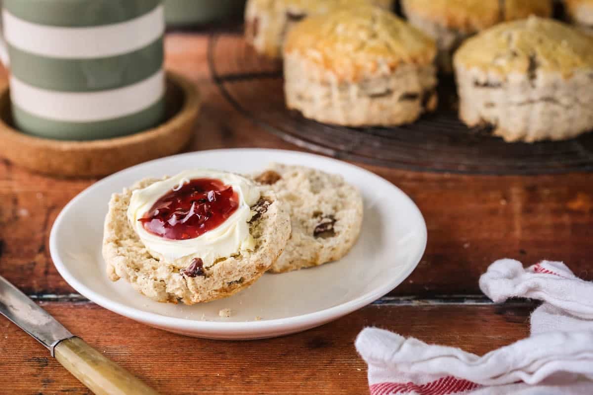 Gluten-free fruit scone halved and layered with clotted cream and fresh homemade jam.