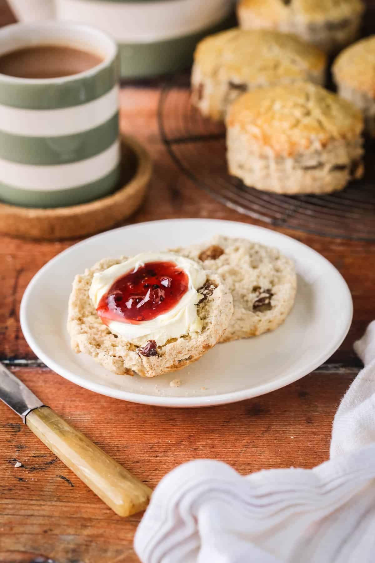 Gluten-free fruit scone halved and layered with clotted cream and fresh homemade jam.