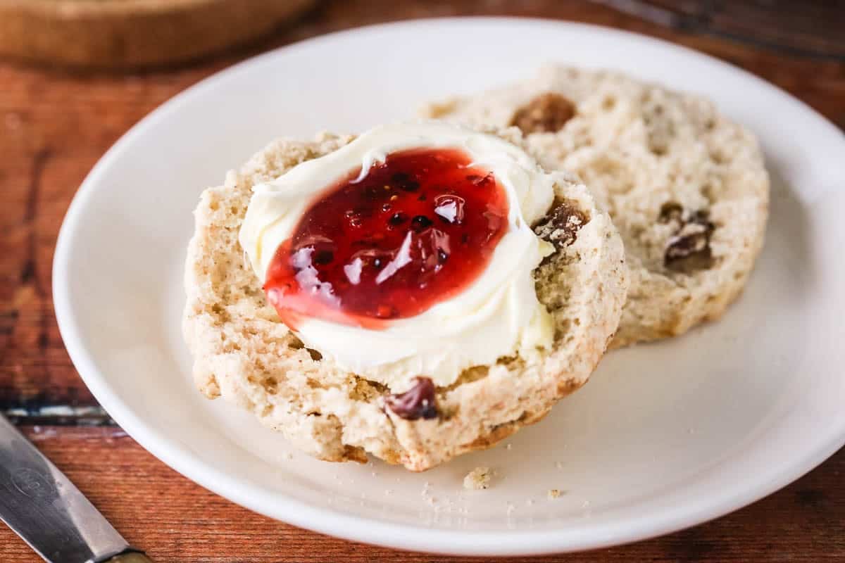 Gluten-free fruit scone halved and layered with clotted cream and fresh homemade jam.