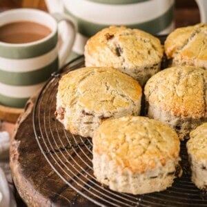 Gluten-free fruit scones on a wire rack next to a cup of tea.