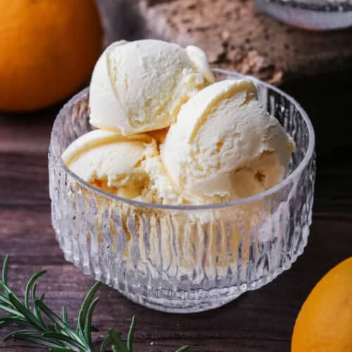 Orange ice cream in a glass bowl.