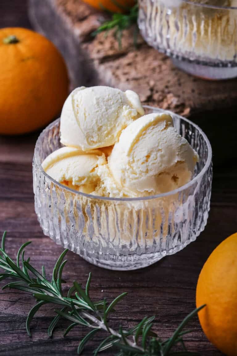 Orange ice cream in a glass bowl.
