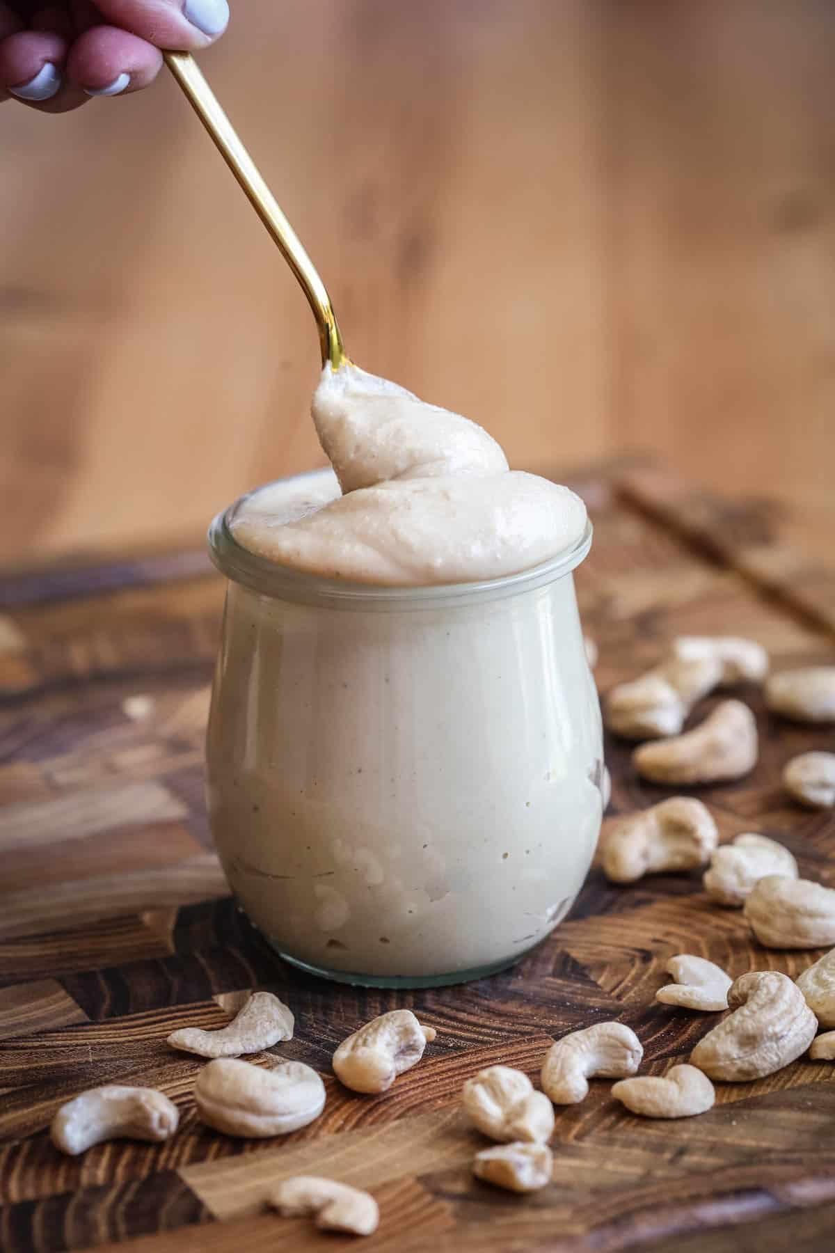 Spoon dipping into creamy cashew butter in a jar.