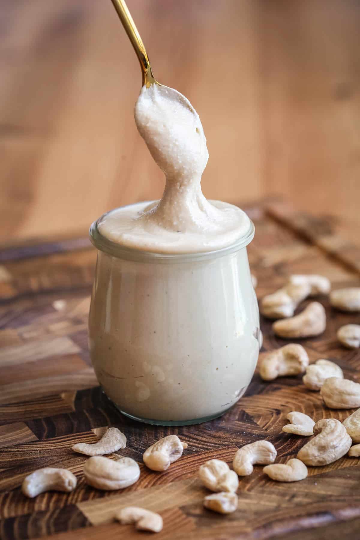 Spoon dipping into creamy cashew butter in a jar.