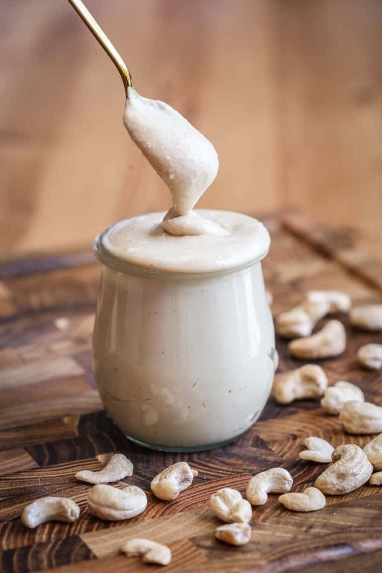 Spoon dipping into creamy cashew butter in a jar.