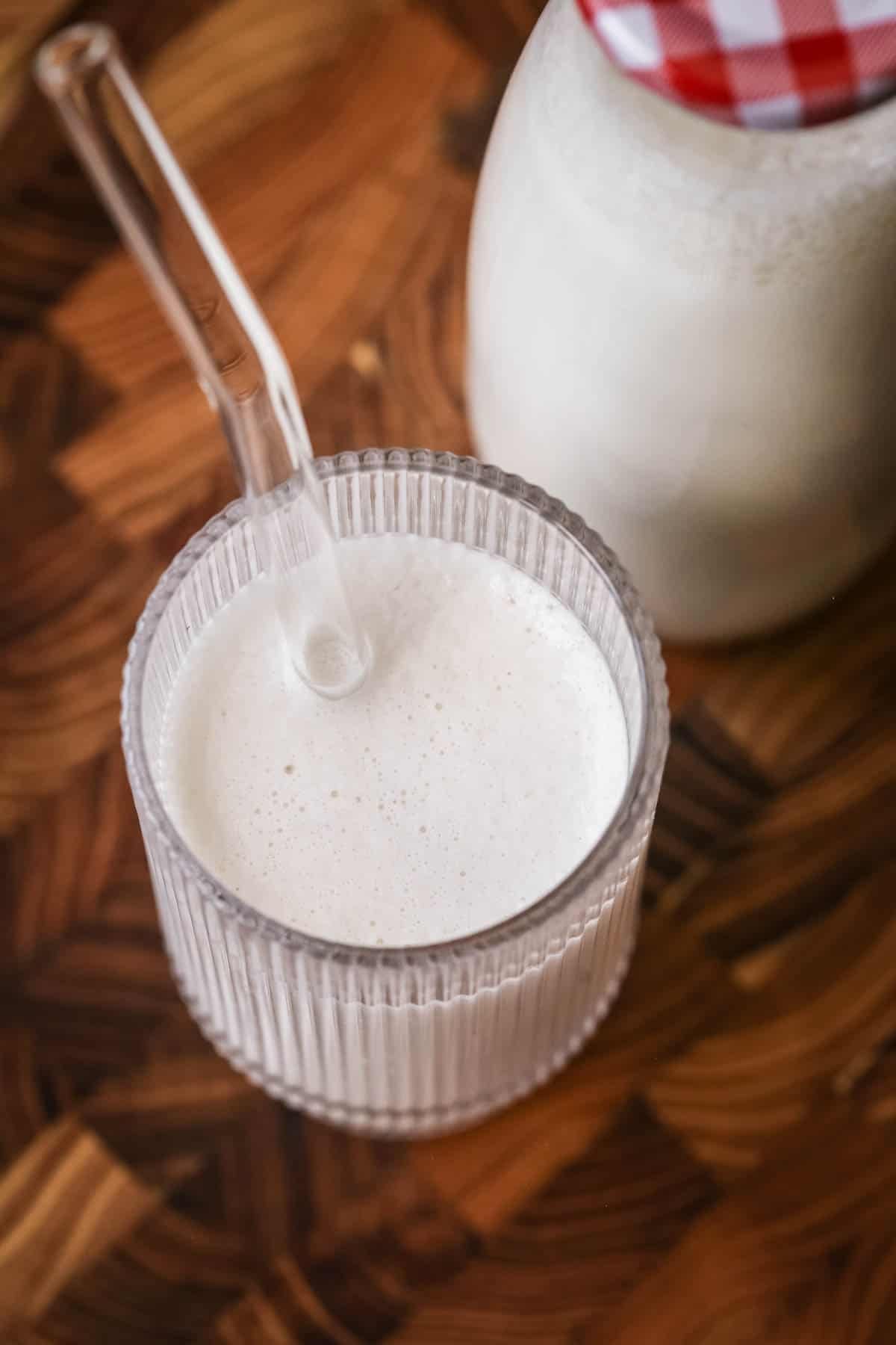 Cashew Nut Milk in a glass with a straw showing frothy creamy milk.