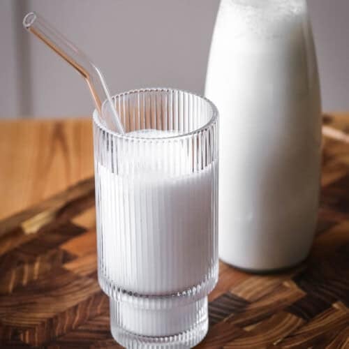 Cashew Nut Milk in a glass in front of full milk bottle.