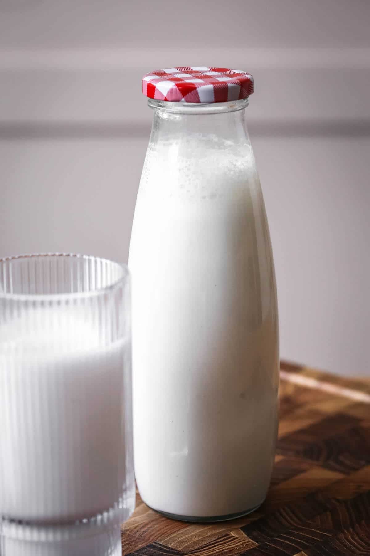 Milk bottle full of cashew milk showing frothy creamy milk.