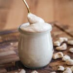 Spoon dipping into creamy cashew butter in a jar.