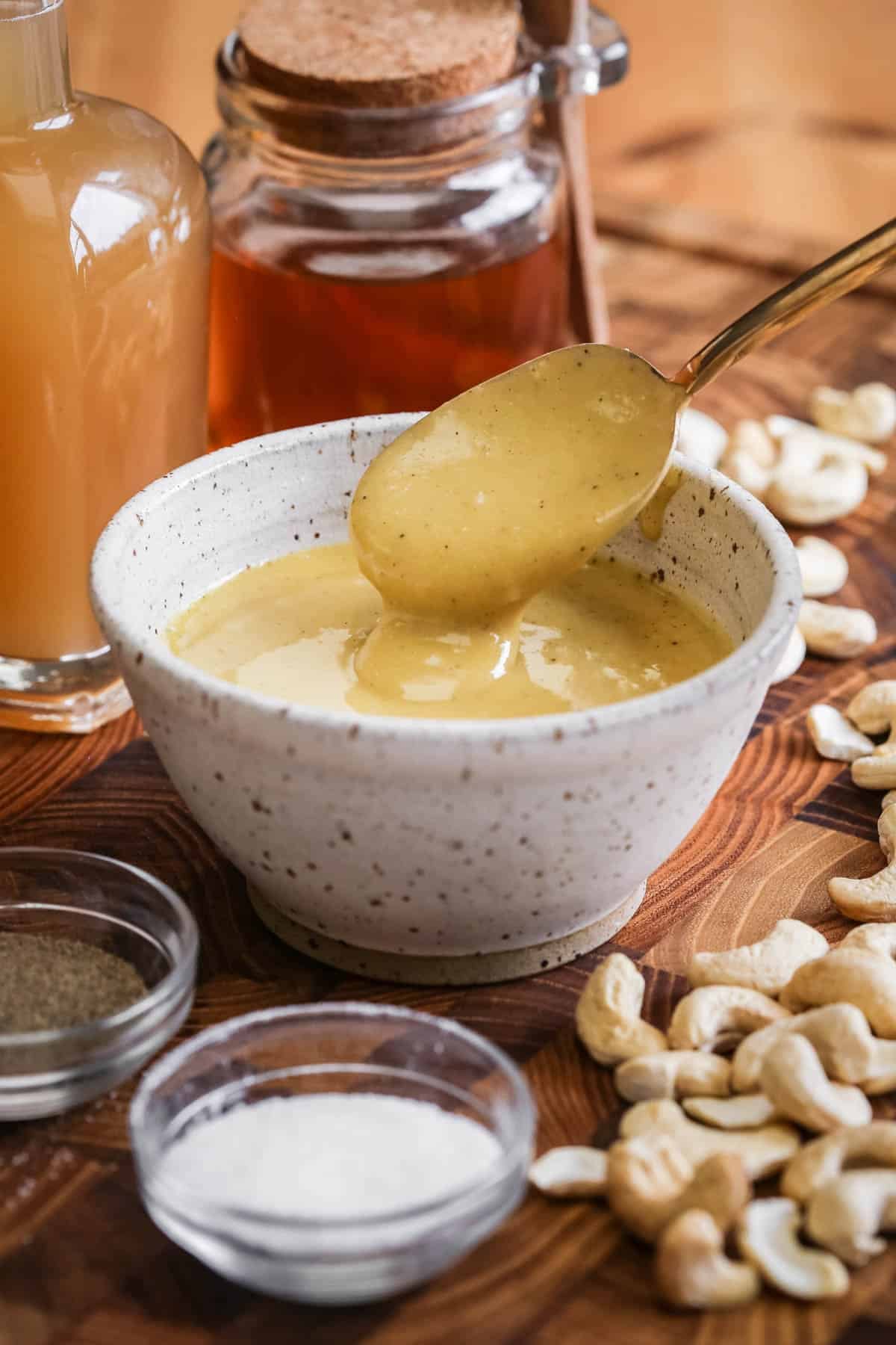 Spoon lifting out ultra creamy cashew dressing from a bowl.