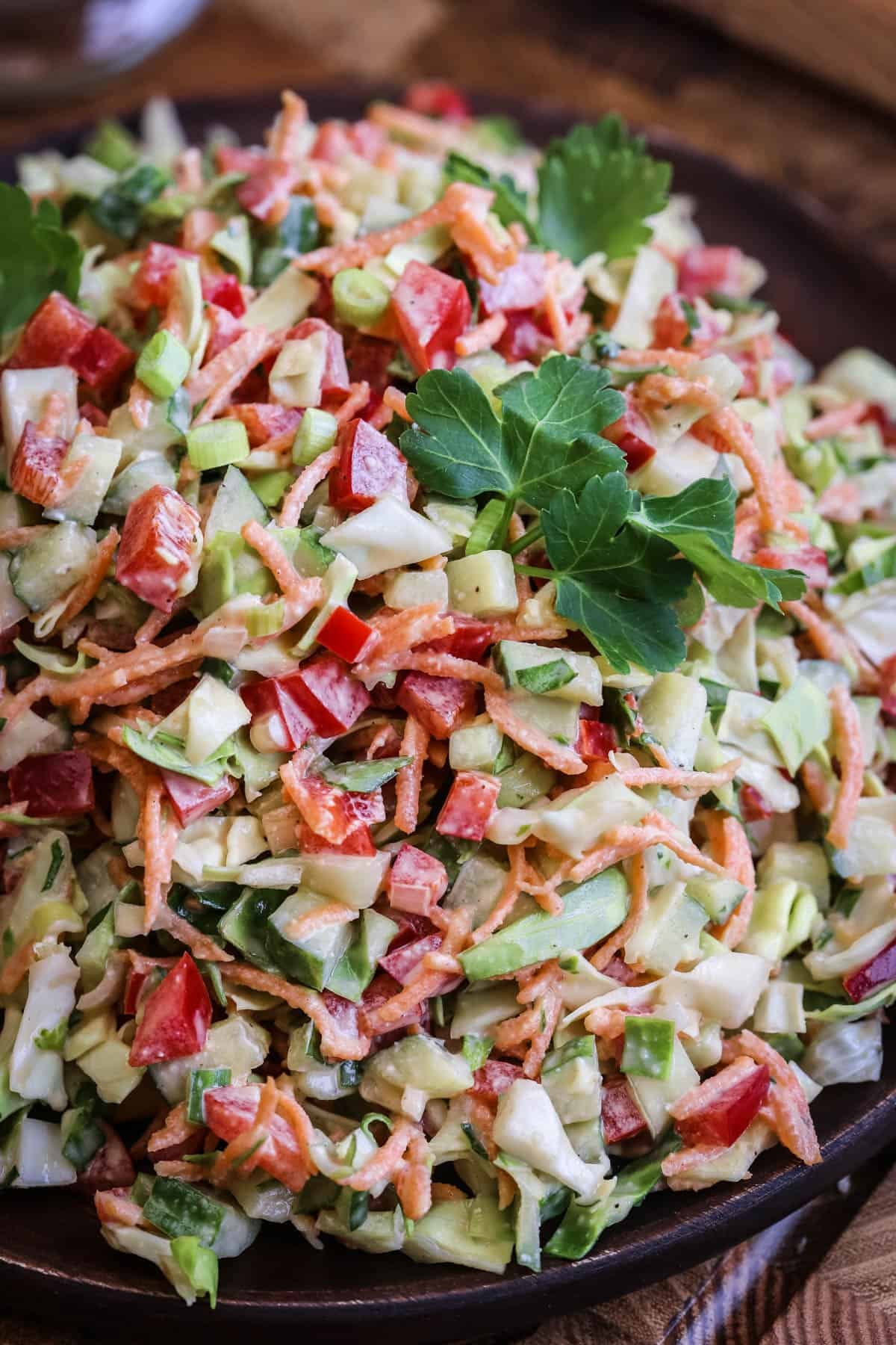 Crunchy Chopped Salad fully dressed and topped with fresh parsley leaves on a serving plate.