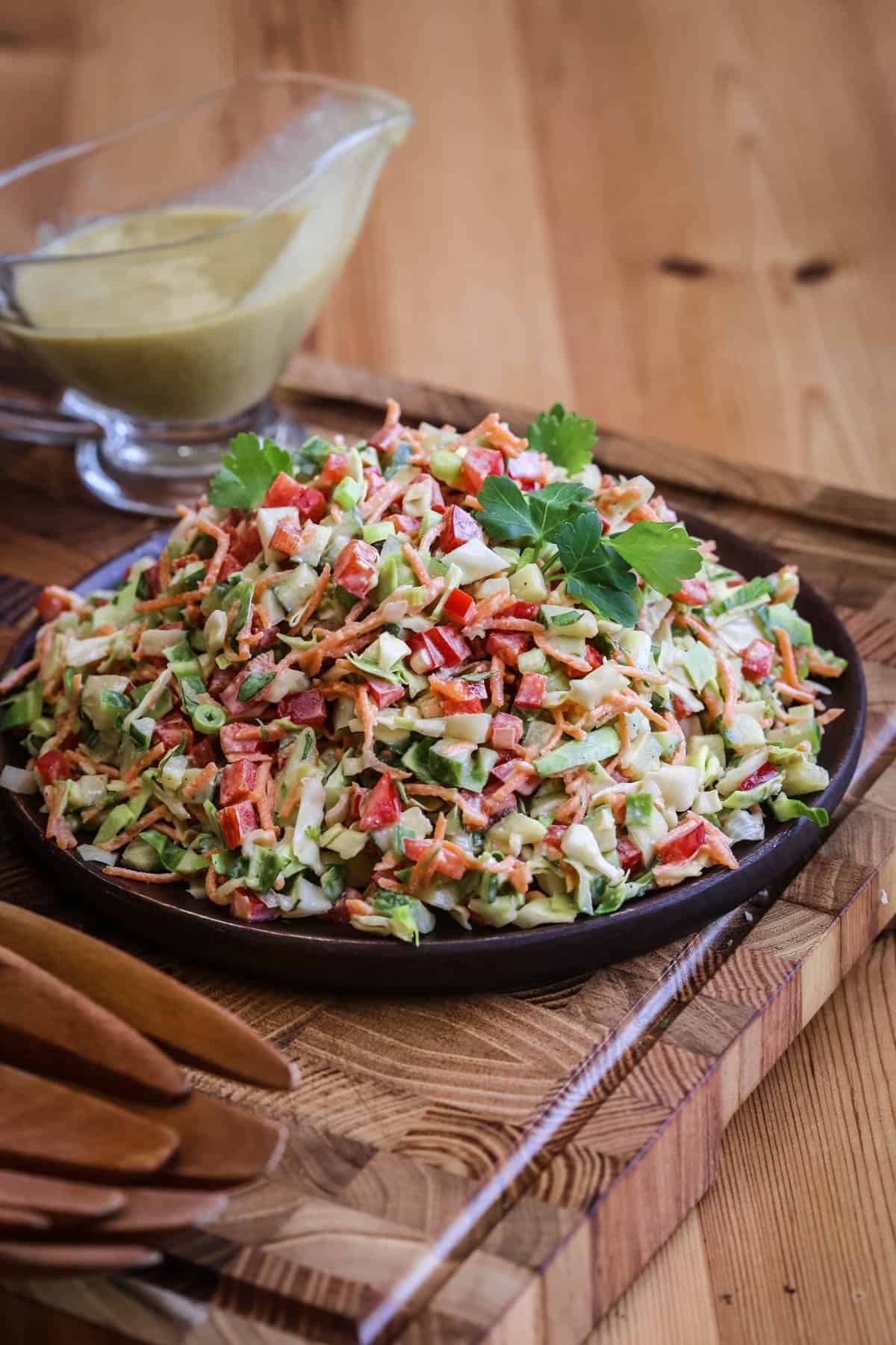 Crunchy Chopped Salad fully dressed and topped with fresh parsley leaves on a serving plate.