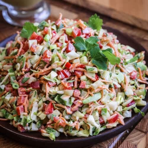 Crunchy Chopped Salad fully dressed and topped with fresh parsley leaves on a serving plate.