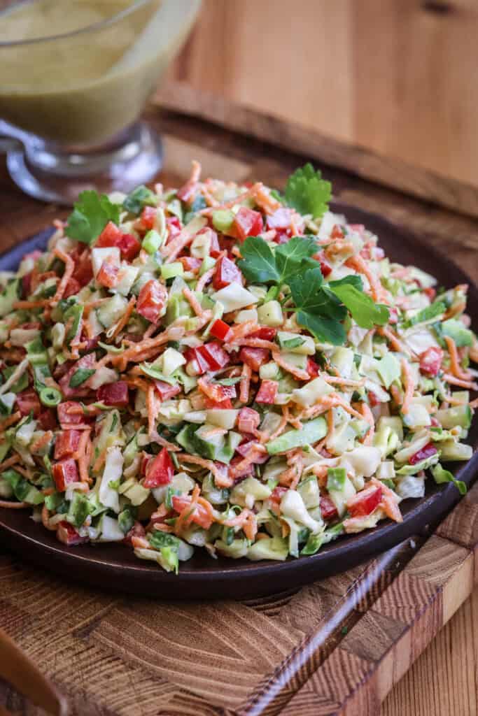 Crunchy Chopped Salad fully dressed and topped with fresh parsley leaves on a serving plate.