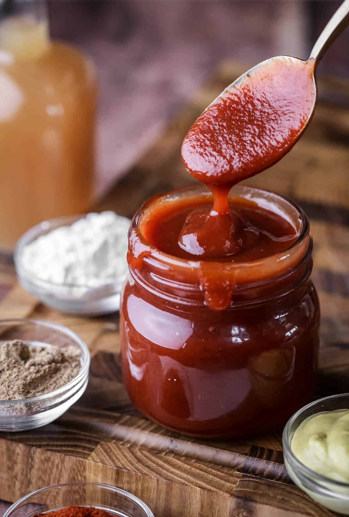 Spoon dipping out of BBQ sauce showing how it's thick and luscious.