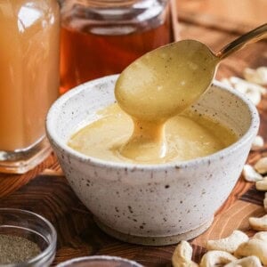 Spoon lifting out ultra creamy cashew dressing from a bowl.