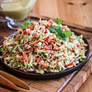 Crunchy Chopped Salad fully dressed and topped with fresh parsley leaves on a serving plate.