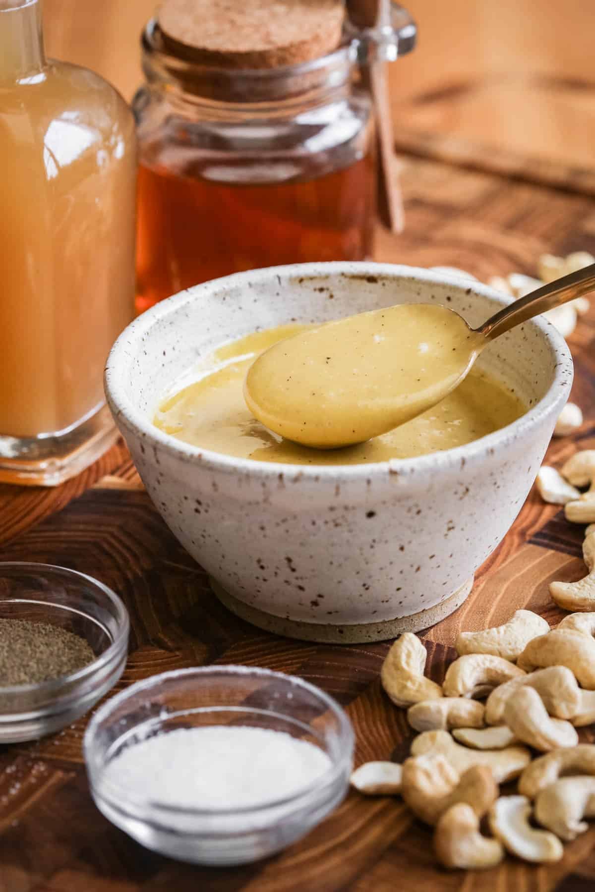 Spoon lifting out ultra creamy cashew dressing from a bowl.