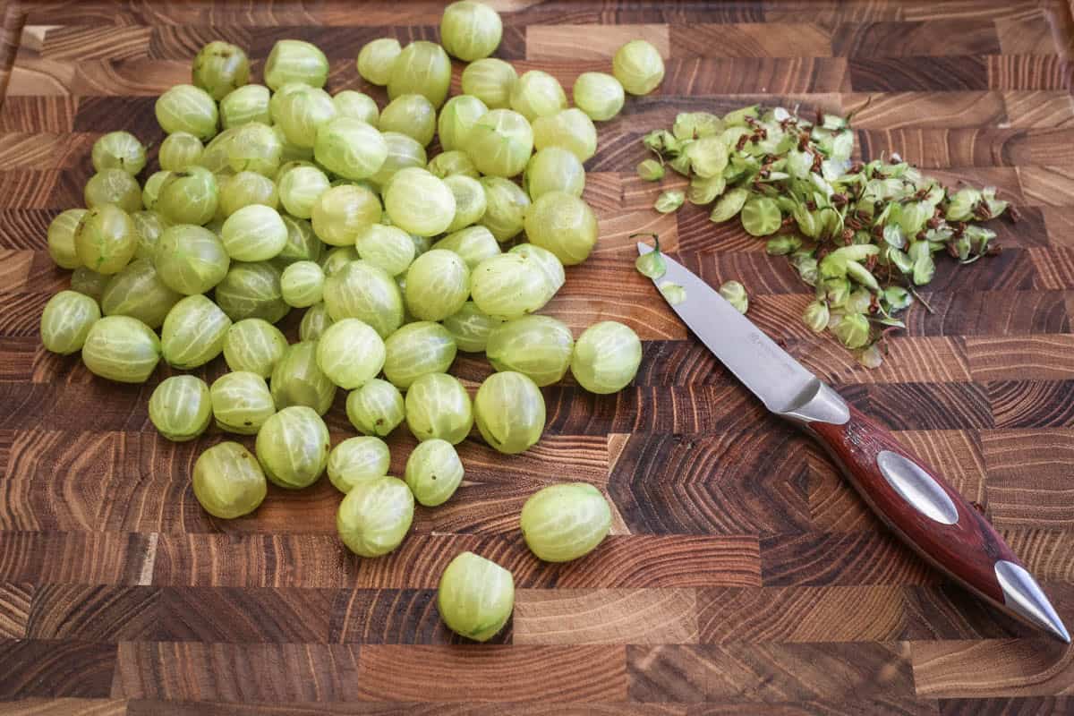 Gooseberry preparation with tops and tails sliced off with sharp knife.
