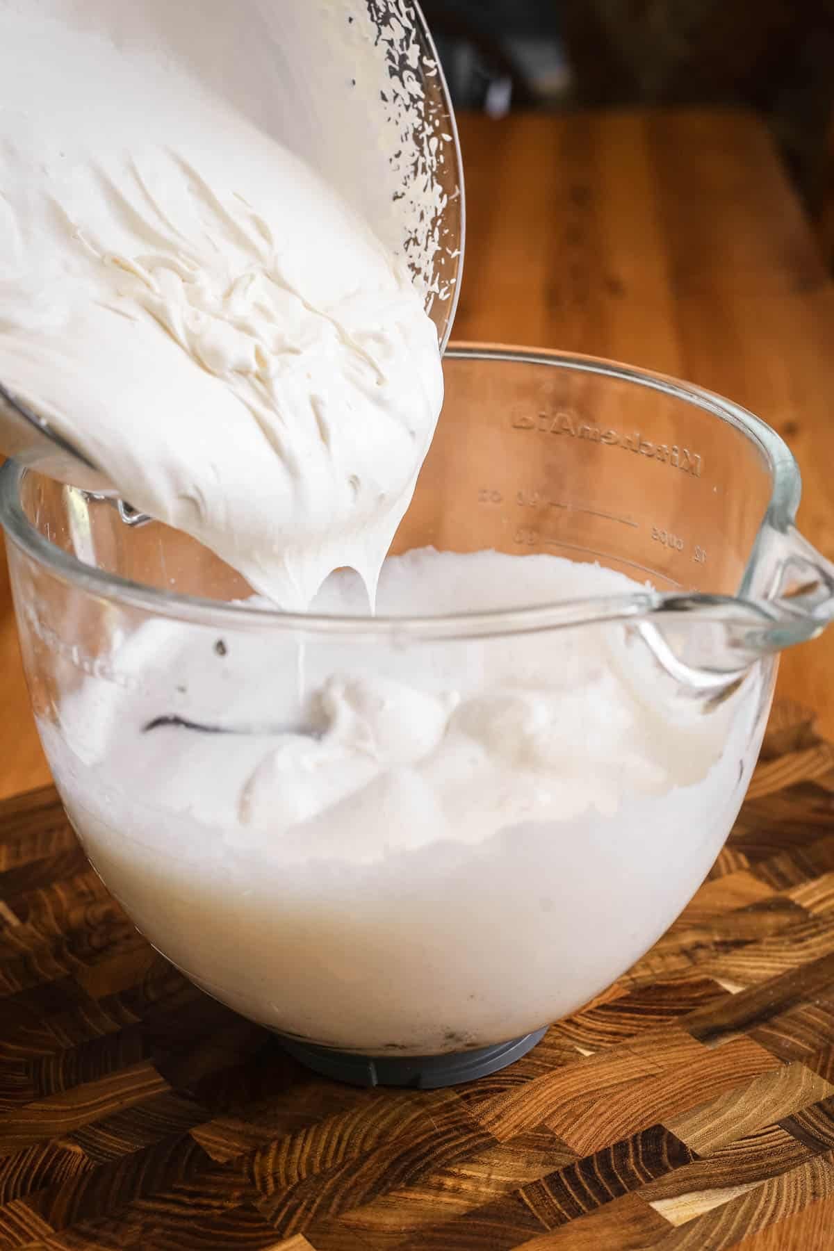 Whipped cream pouring into aquafaba and sugar syrup ice cream base.