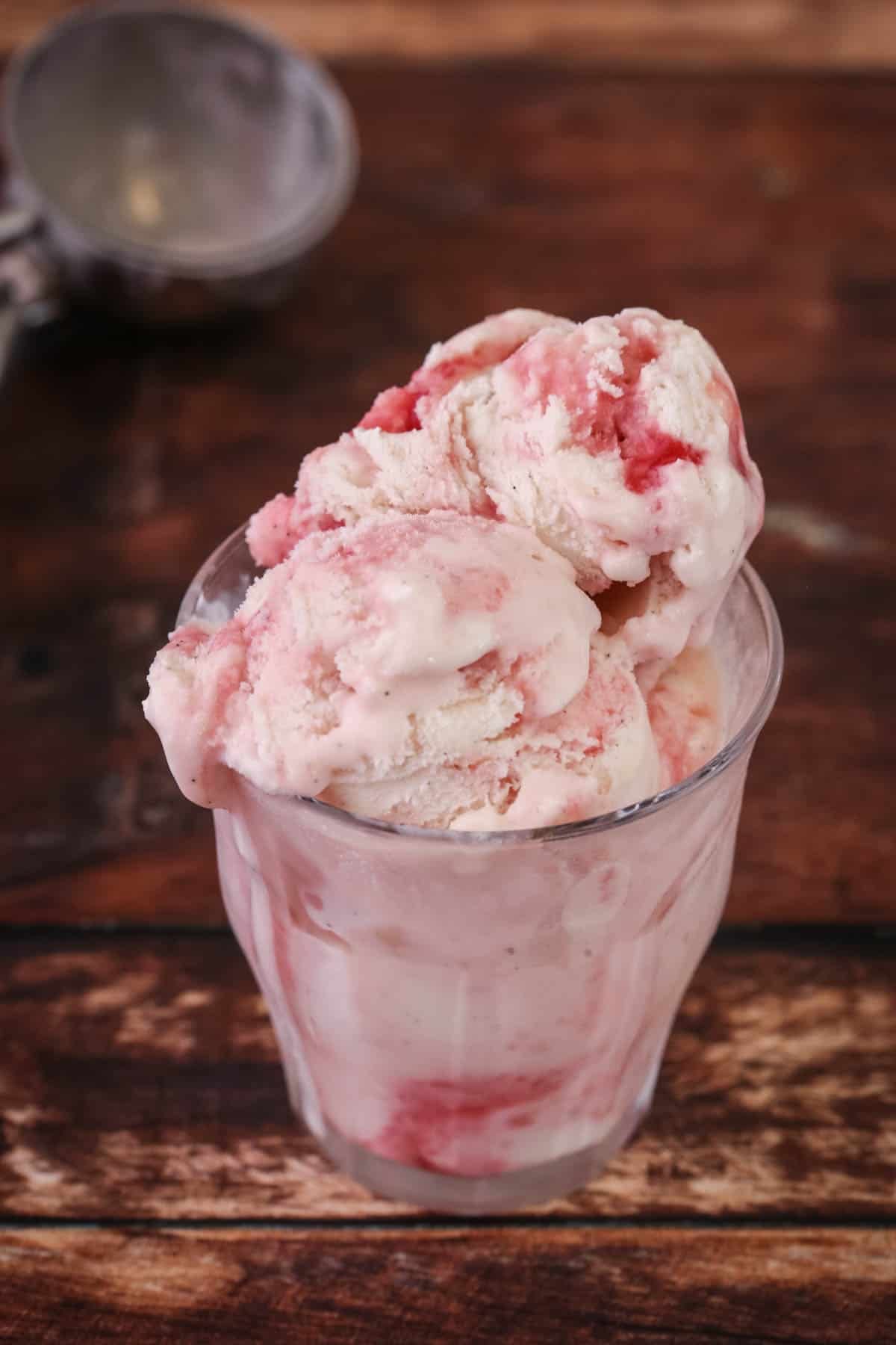 Vegan Raspberry Ripple Ice Cream scooped into a glass showing gorgeously creamy texture.