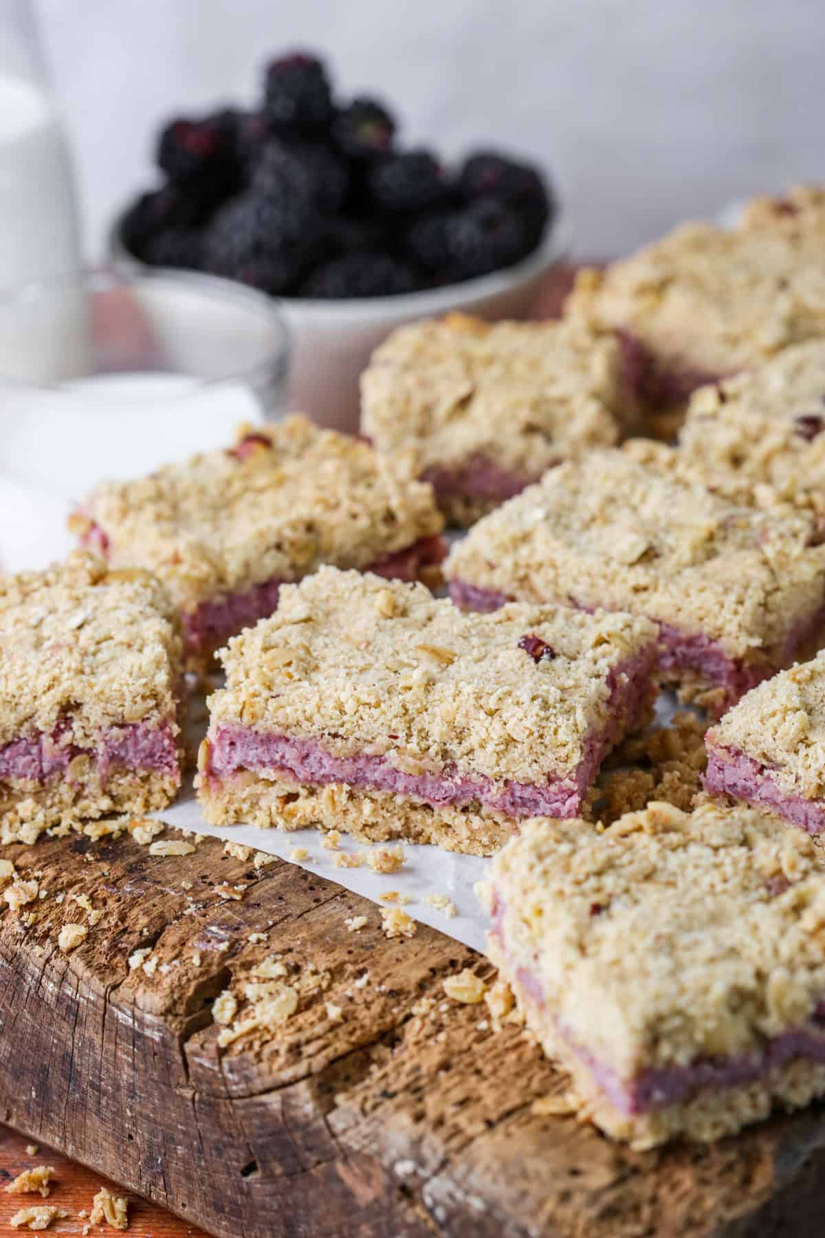 Gluten-Free Blackberry Bars on a wooden board with creamy blackberry cheesecake filling and buttery crumble layers.