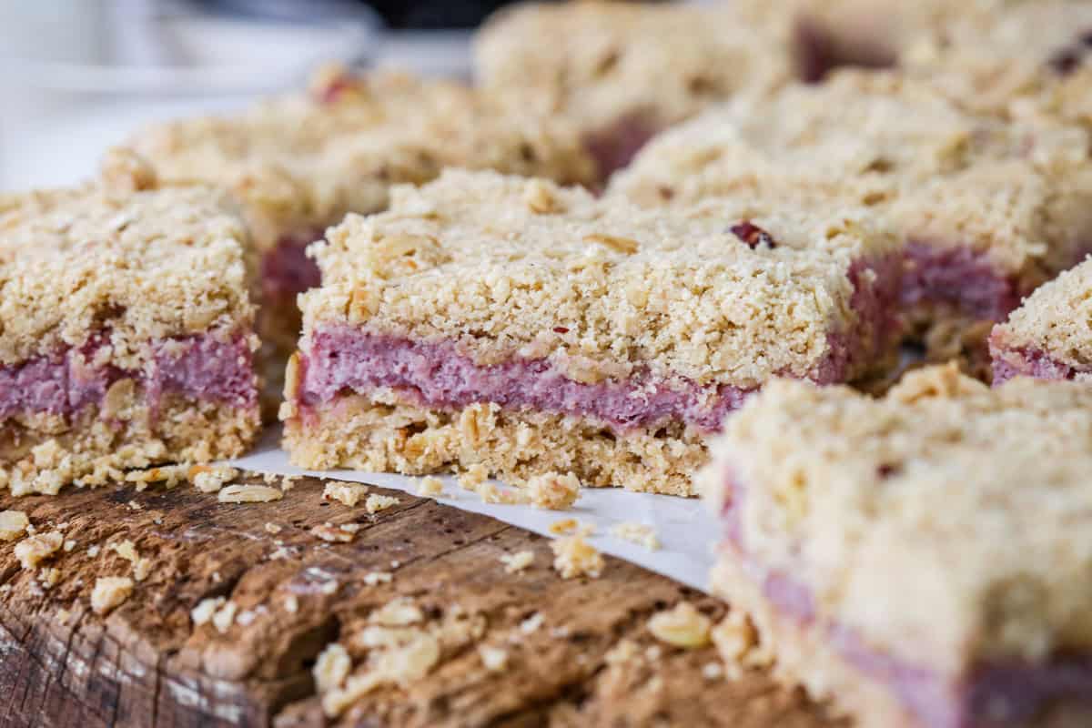 Gluten-Free Blackberry Bars on a wooden board with creamy blackberry cheesecake filling.