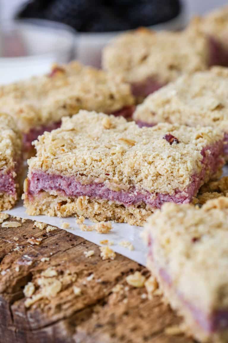 Gluten-Free Blackberry Bars on a wooden board with creamy blackberry cheesecake filling.