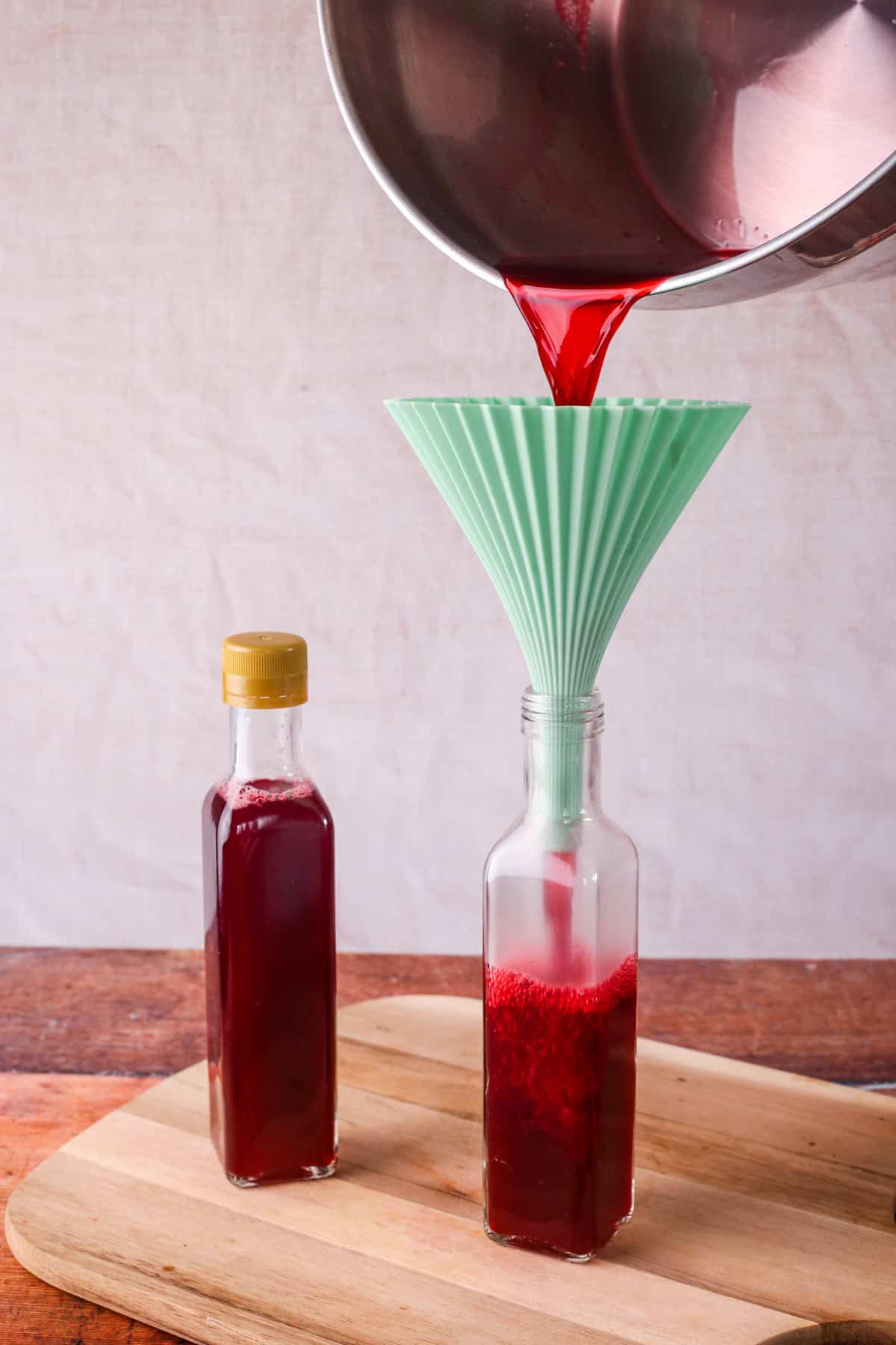 Vinegar poured from stainless steel preserving pan through a funnel into a sterilised glass bottle.