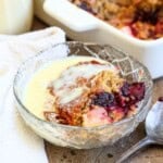Bowl of Gluten-Free Blackberry Apple Sponge Pudding drenched in custard.