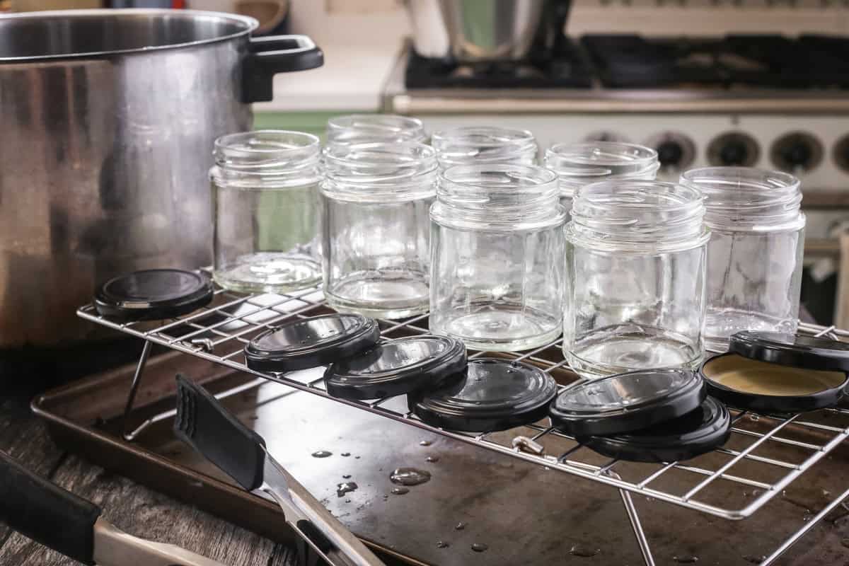 Glass jars and lids drying on a wire rack.