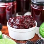 Blackberry Lime Jam in a pot surrounded by limes and blackberries.