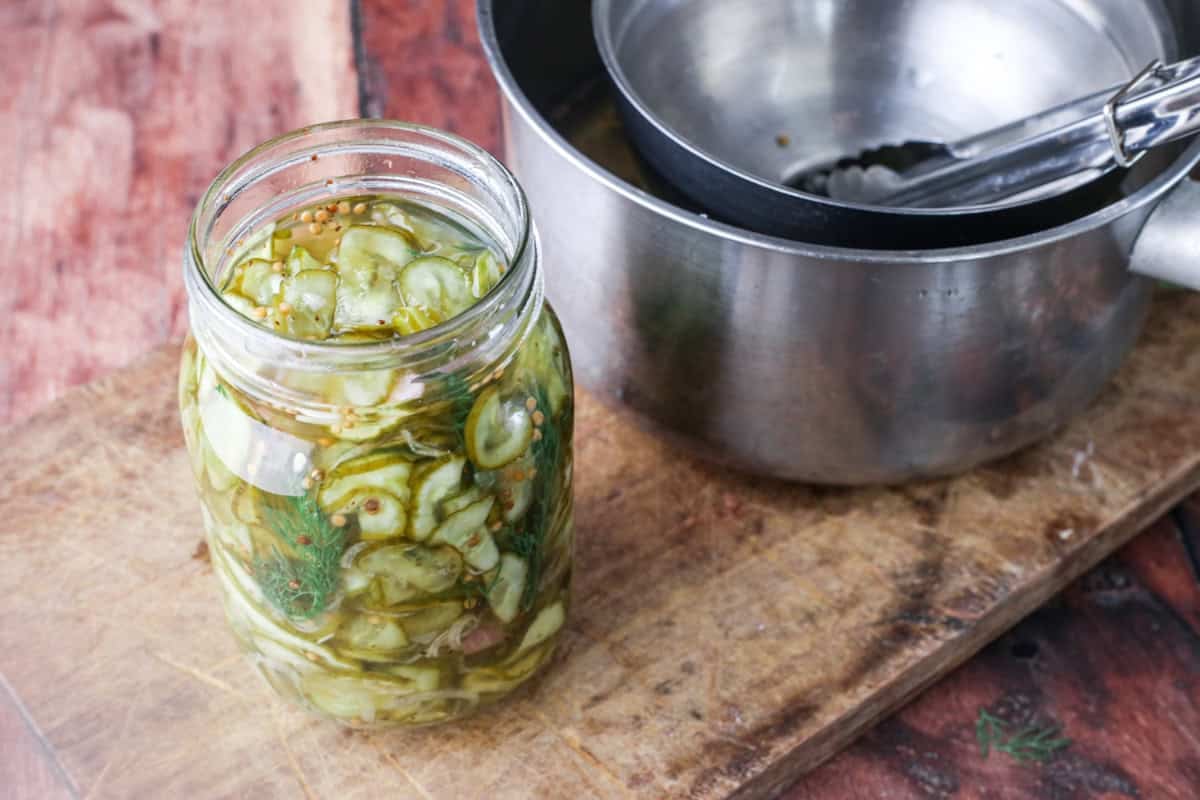 Jar filled with pickled cucumbers and shallots and covered with the pickling vinegar.