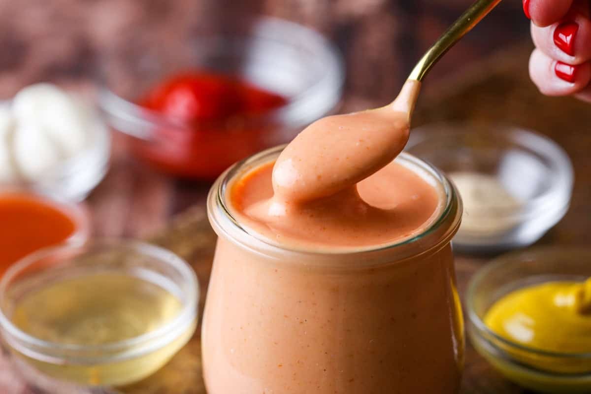 Spooning thick and creamy burger sauce from jar.