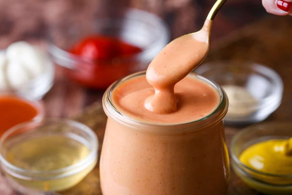 Spooning thick and creamy burger sauce from jar.