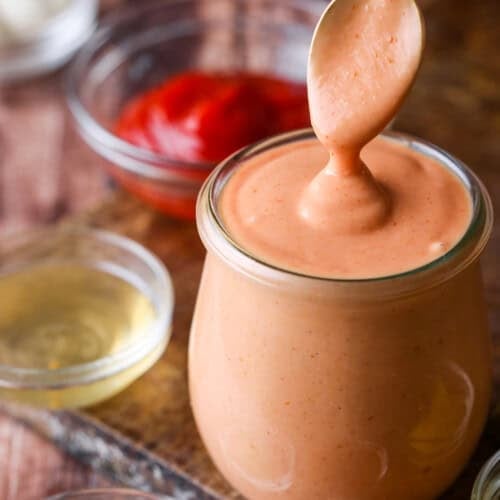 Spooning thick and creamy burger sauce from jar.