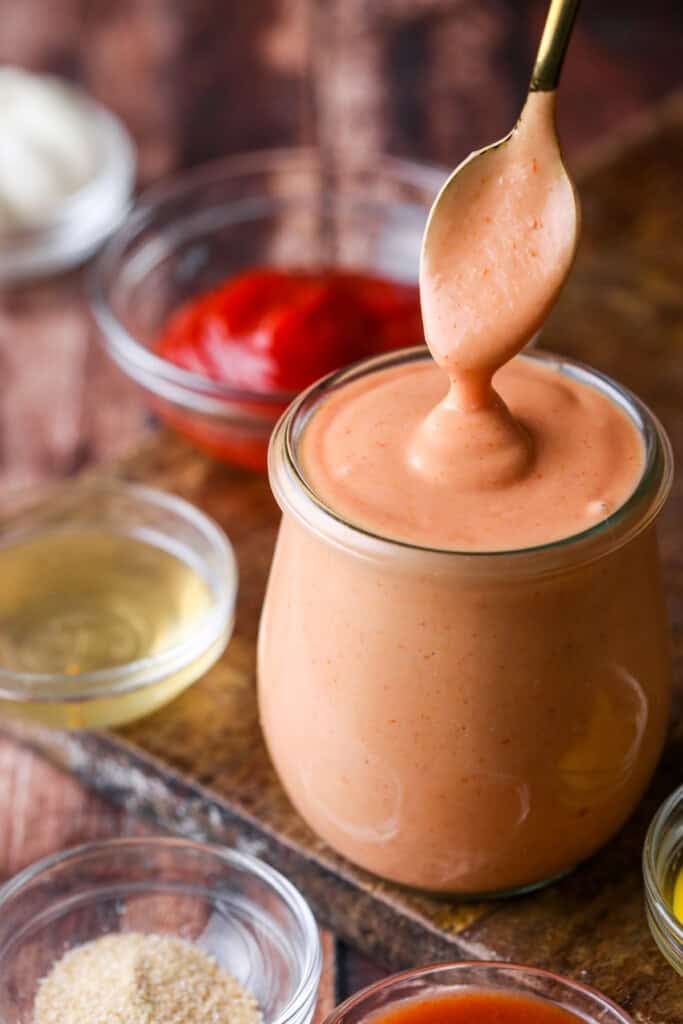 Spooning thick and creamy burger sauce from jar.