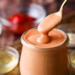 Spoon dipping into jar of buffalo burger sauce.