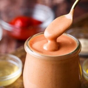 Spoon dipping into jar of buffalo burger sauce.